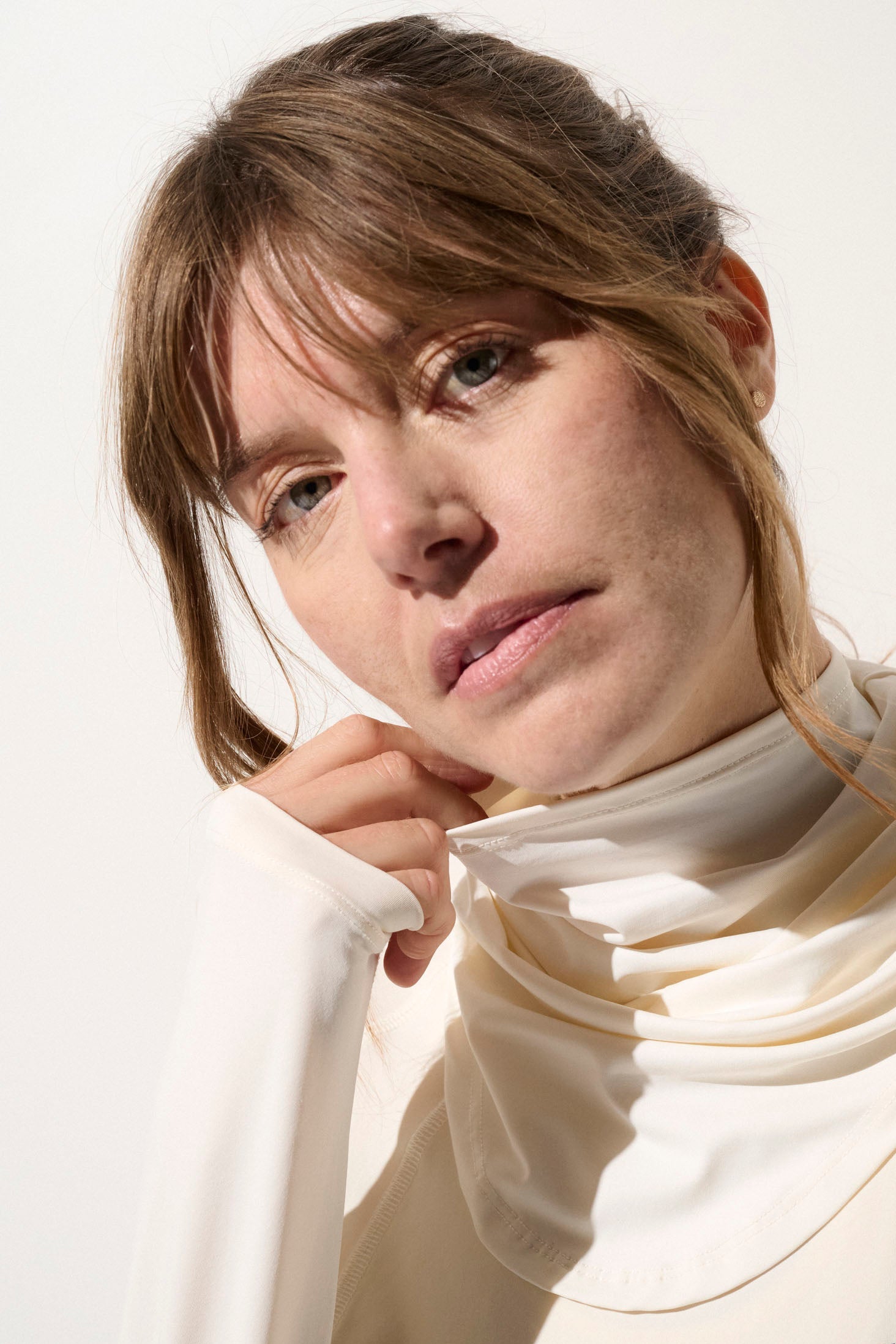 Femme portant un tour de cou anti-UV blanc UPF 50+, léger et extensible pour protection solaire quotidienne.