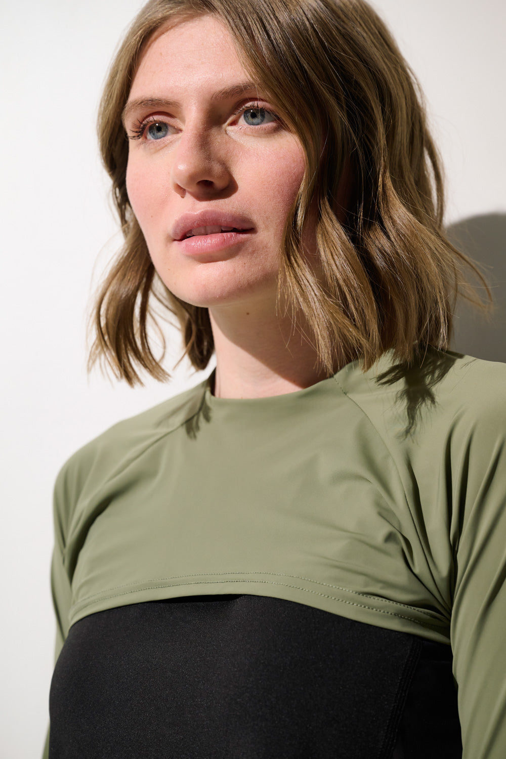 Femme portant un shrug anti-UV - Sequoia noir et vert, coupe élégante et respirante, protection solaire UPF 50+.