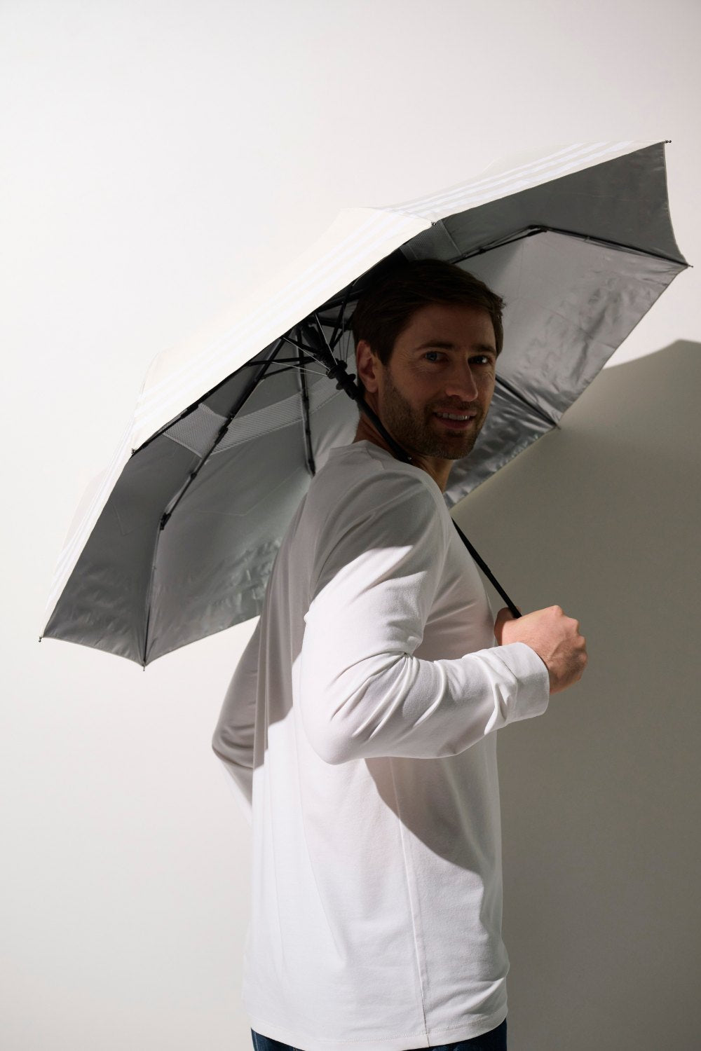 Homme souriant portant une ombrelle anti-UV - Pornichet, protection solaire UPF 50+ sous un ciel clair.