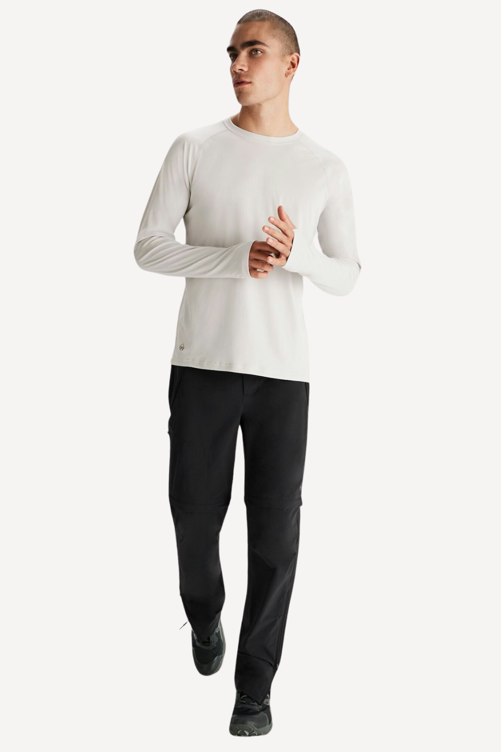 Homme portant un t-shirt anti-UV blanc UPF 50+ et un pantalon noir, parfait pour les activités de plein air.