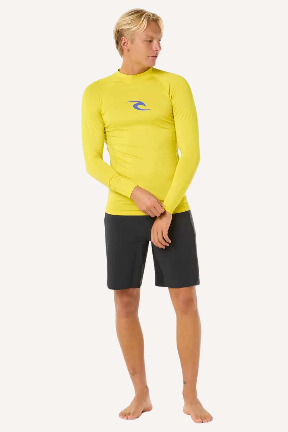 Homme en t-shirt de bain anti-UV jaune Rip Curl, manches longues, UPF 50+, idéal pour la plage et le surf.