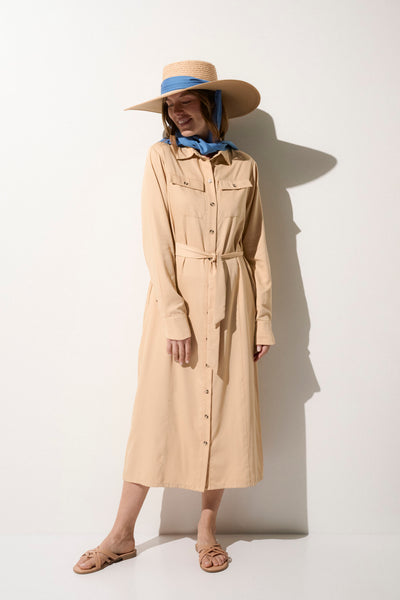 Femme portant une robe légère beige anti-UV UPF50+, idéale pour une journée ensoleillée.