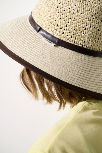 Chapeau anti-UV - Antibes, beige avec large bord, offrant une protection solaire UPF 50+, porté par une femme.