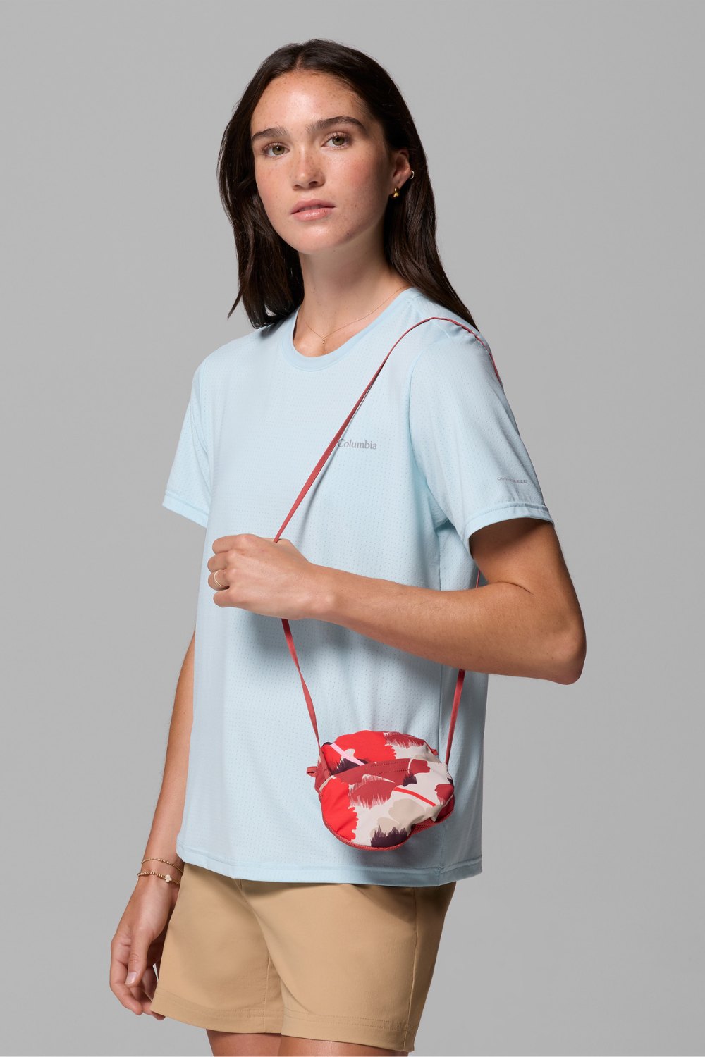Femme portant un t-shirt anti-UV bleu, avec un sac bandoulière floral, pour un look décontracté et élégant.