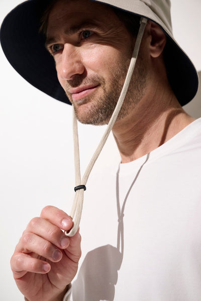 Homme avec un bob anti-UV - Faro beige, léger et pratique, offrant une protection solaire UPF 50+.