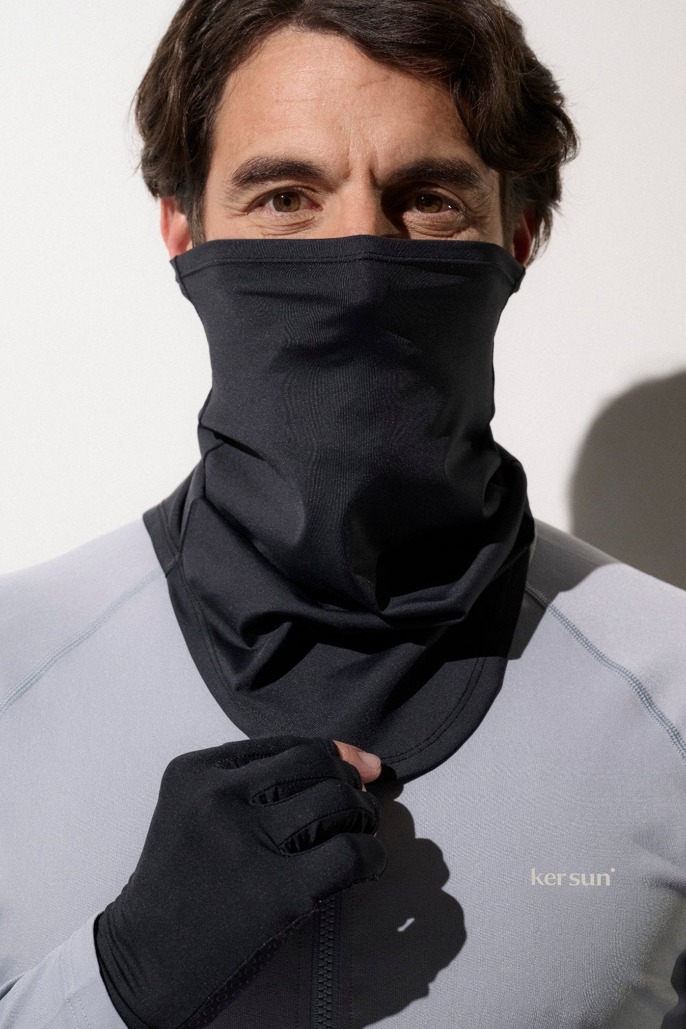Homme portant un tour de cou anti-UV noir UPF 50+, idéal pour activités sportives et protection solaire.