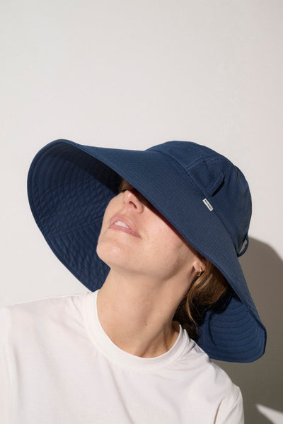 Chapeau anti-UV bleu pour femme, offrant une protection solaire avec un large bord et une jugulaire ajustable.