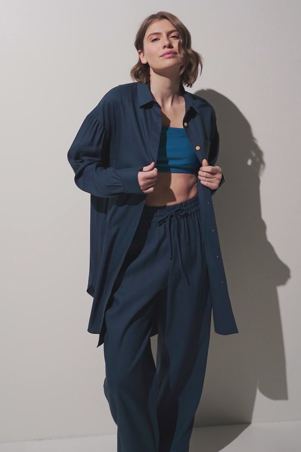 Femme portant une chemise longue anti-UV - Sylt, élégante et légère, avec un pantalon assorti.